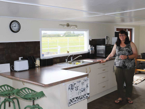 Stacy Faith standing in the kitchen of the old, disused dairy shed on her farm that has been converted into an AirBnB.