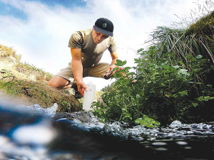 Programme co-lead Uwe Morgenstern takes a water sample from a spring-fed stream. Photo Credit: GNS Science