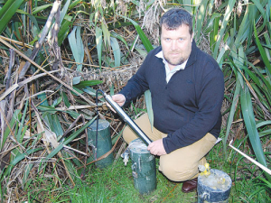 Lincoln Agritech group manager environmental research, Blair Miller, holds a prototype of Agritech’s real-time optical nitrate sensor beside the sampling bores at the Lincoln University Dairy Farm that have been used in the device’s development. 