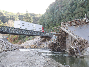 The crumbled remains of the Waikare bridge with only a single lane Bailey bridge as a temporary replacement.